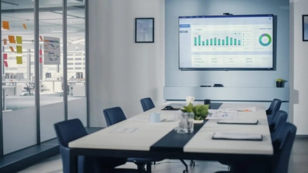 غرفة اجتماعات تحتوي على مكتب وشاشة توضح رسم بياني